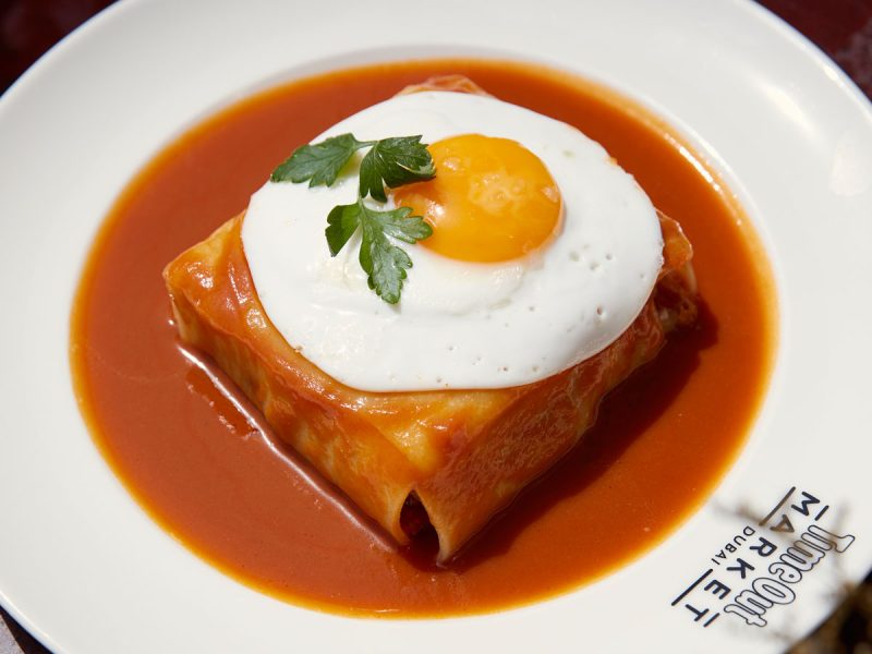 Time Out Market Dubai new dishes: wrapped pastry with egg in tomato sauce on a white Time Out Market plate